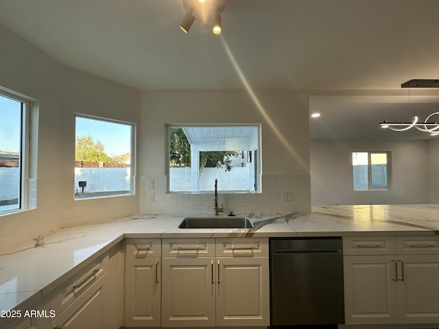 kitchen with light stone countertops, sink, white cabinetry, and pendant lighting