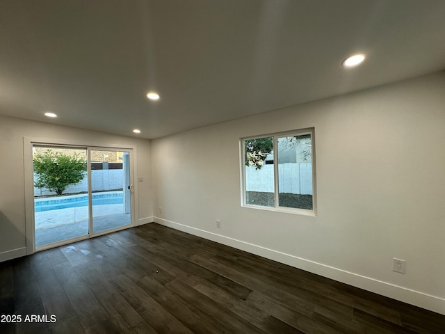 unfurnished room with a healthy amount of sunlight and dark wood-type flooring