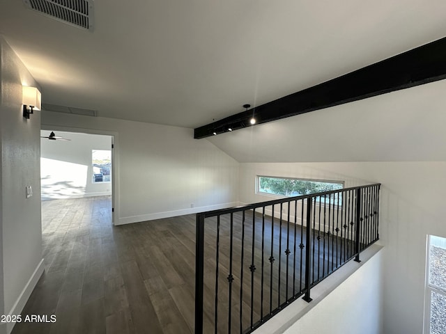 hallway with lofted ceiling with beams, dark wood-type flooring, and a wealth of natural light