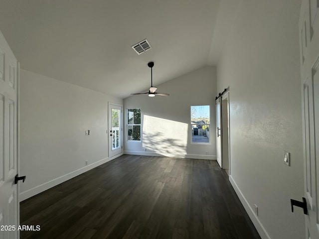 interior space with ceiling fan, dark hardwood / wood-style flooring, a barn door, and vaulted ceiling