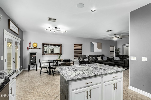 kitchen featuring white cabinetry, a center island, light stone counters, ceiling fan, and stainless steel dishwasher