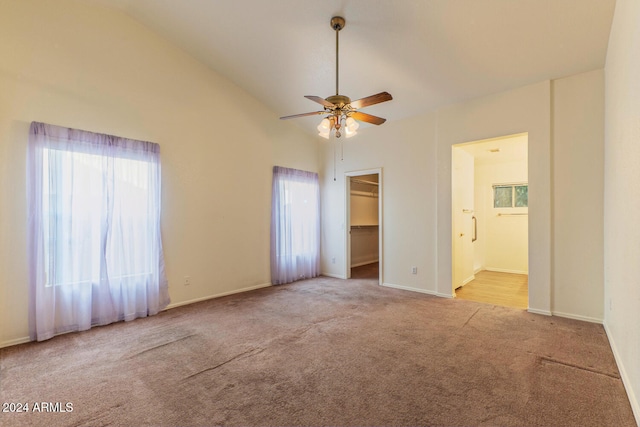 unfurnished bedroom featuring ensuite bathroom, a walk in closet, vaulted ceiling, ceiling fan, and a closet