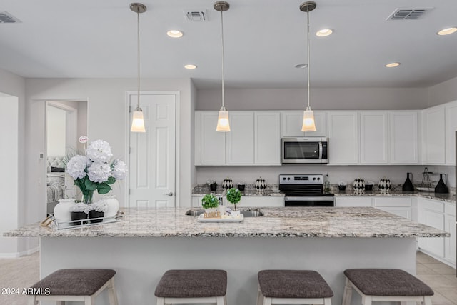 kitchen with pendant lighting, a center island with sink, appliances with stainless steel finishes, and white cabinetry