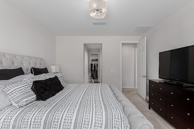 bedroom featuring a spacious closet, a closet, and light carpet