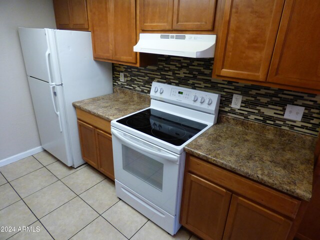 kitchen featuring dark stone countertops, light tile patterned floors, backsplash, white appliances, and exhaust hood