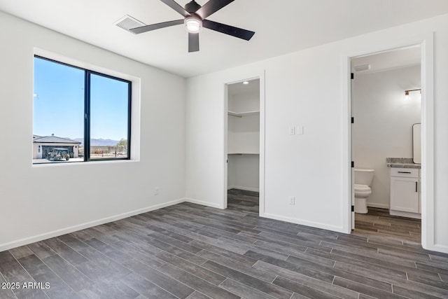20111 W Saguaro Vista Dr, Wittmann, AZ 85361 - unfurnished bedroom featuring dark wood finished floors, baseboards, a closet, a spacious closet, and ensuite bathroom