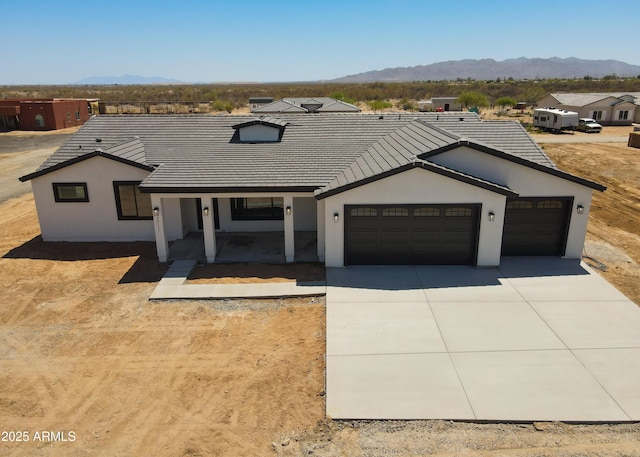 20111 W Saguaro Vista Dr, Wittmann, AZ 85361 - view of front facade featuring a tiled roof, driveway, a garage, a mountain view, and stucco siding