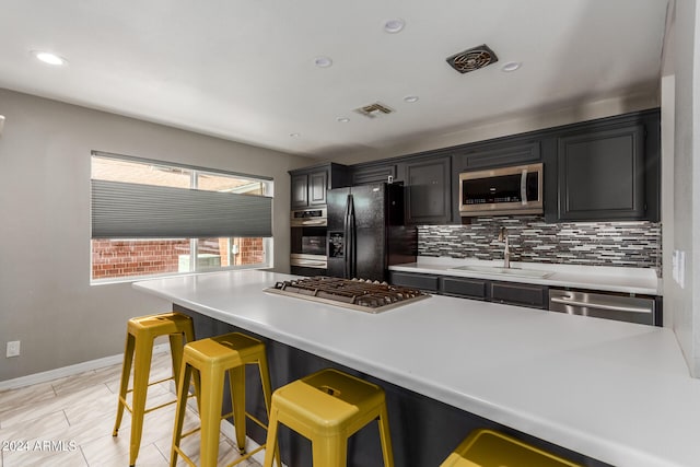 kitchen featuring light tile patterned flooring, tasteful backsplash, sink, a breakfast bar, and appliances with stainless steel finishes