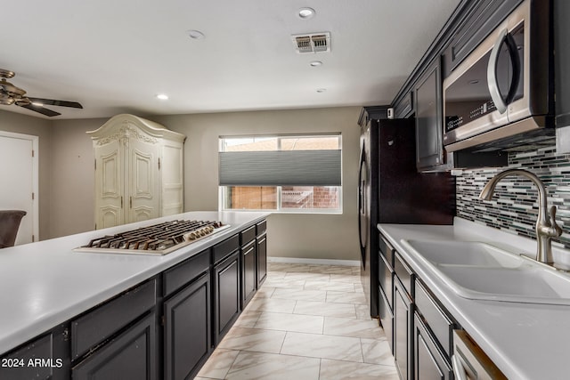 kitchen featuring appliances with stainless steel finishes, sink, backsplash, light tile patterned floors, and ceiling fan