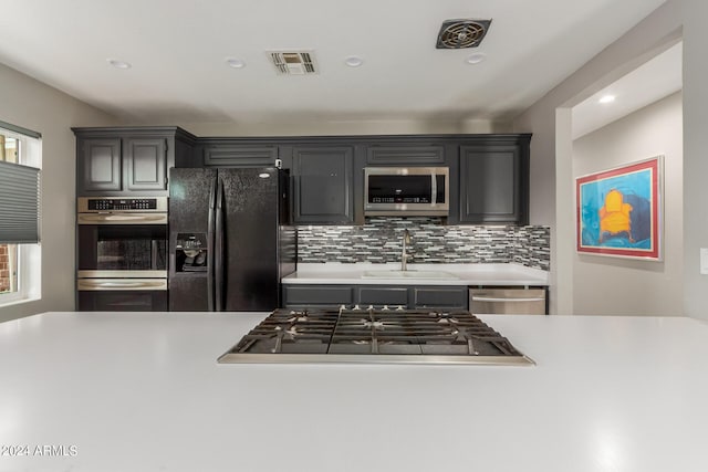 kitchen with backsplash, appliances with stainless steel finishes, and sink