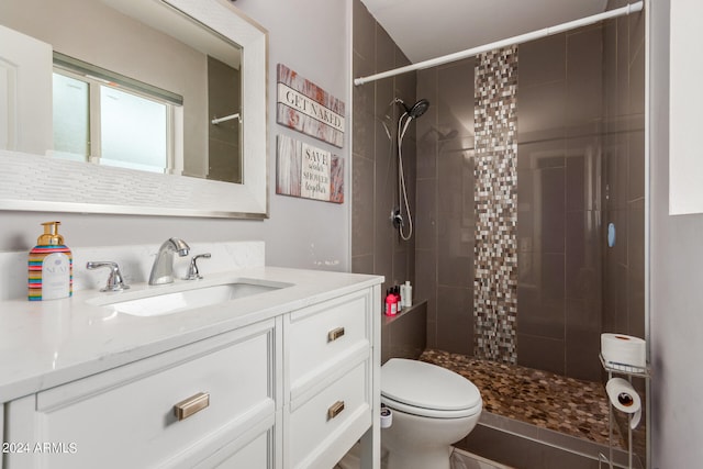 bathroom featuring vanity, tiled shower, and toilet