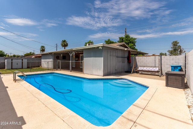 view of swimming pool with a storage shed and a patio