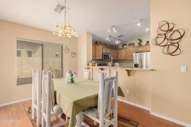 dining room with light wood-type flooring, lofted ceiling, and a chandelier