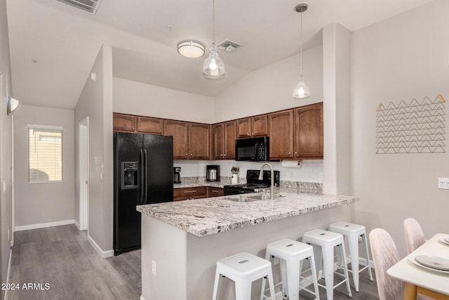 kitchen with lofted ceiling, sink, black appliances, pendant lighting, and backsplash