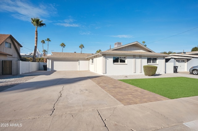 ranch-style house with a chimney, a front yard, fence, a garage, and driveway