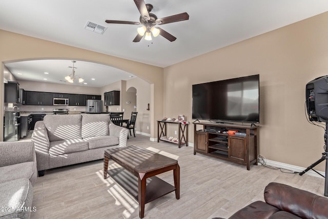 living room featuring ceiling fan with notable chandelier and light hardwood / wood-style flooring