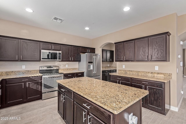 kitchen featuring dark brown cabinetry, a center island, light wood-type flooring, and appliances with stainless steel finishes