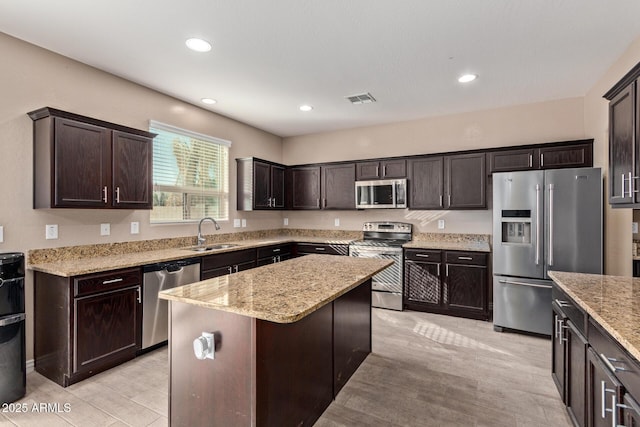 kitchen featuring dark brown cabinetry, a center island, stainless steel appliances, and sink