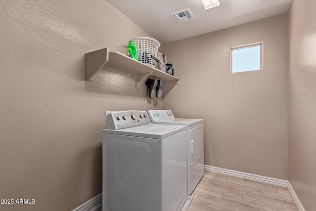 laundry area with light wood-type flooring and separate washer and dryer