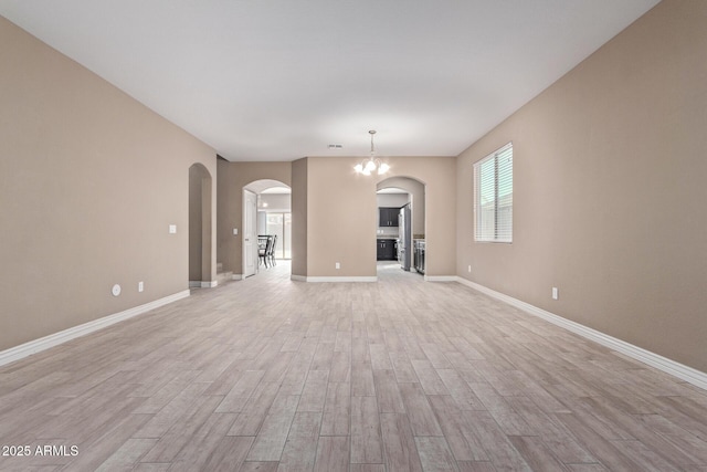 unfurnished living room with light hardwood / wood-style flooring and a notable chandelier