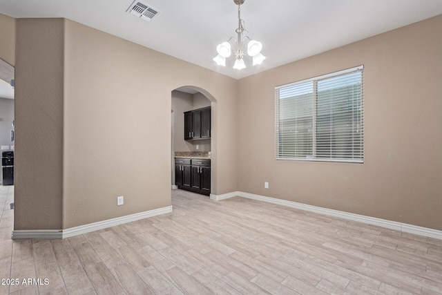 unfurnished living room featuring a notable chandelier and light wood-type flooring