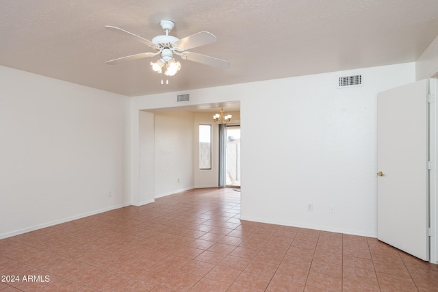 tiled spare room featuring ceiling fan with notable chandelier