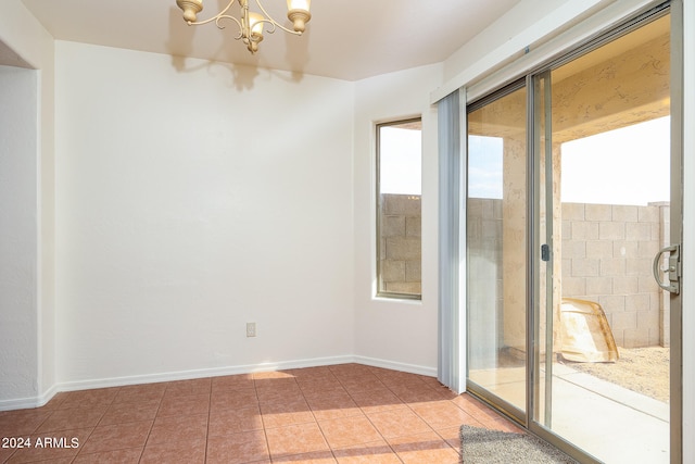 empty room featuring tile patterned flooring and a chandelier