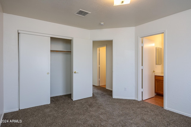 unfurnished bedroom with ensuite bath, a closet, and carpet flooring