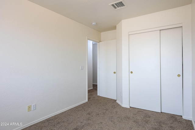 unfurnished bedroom with dark colored carpet and a closet