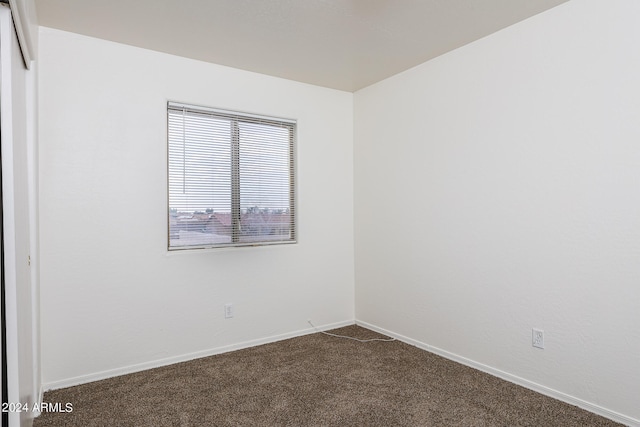 unfurnished room with dark colored carpet