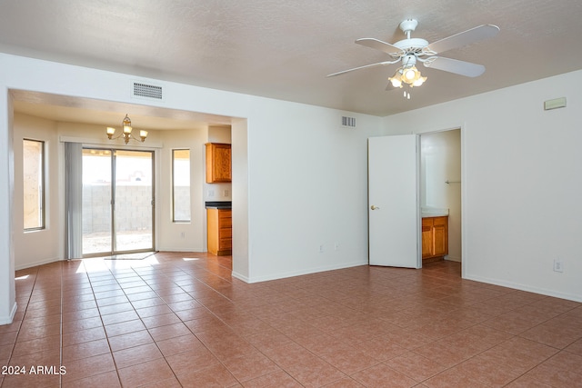 tiled empty room with ceiling fan with notable chandelier and a textured ceiling