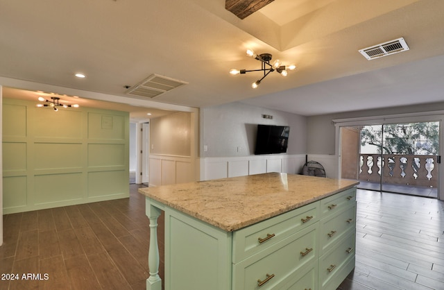 kitchen with a center island, an inviting chandelier, green cabinetry, dark hardwood / wood-style floors, and light stone counters