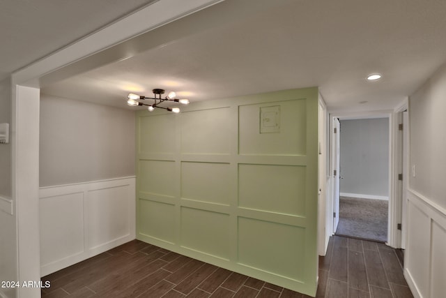 spare room with a chandelier and dark wood-type flooring