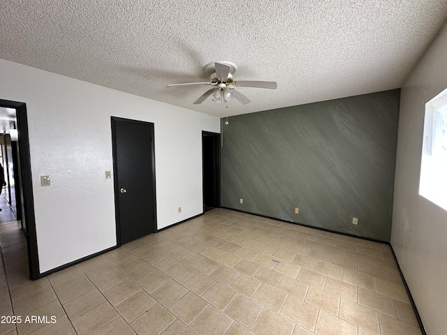 220 S Old Litchfield Rd Unit 104, Litchfield Park, AZ 85340 - unfurnished bedroom with a textured ceiling, a ceiling fan, an accent wall, and light tile patterned flooring