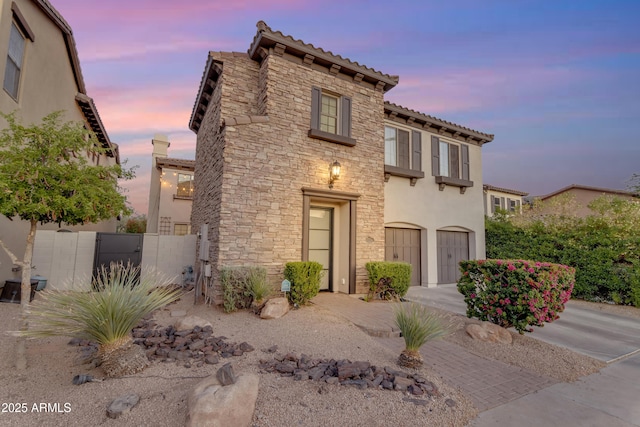 view of front of home featuring stone siding, stucco siding, a garage, and a tiled roof