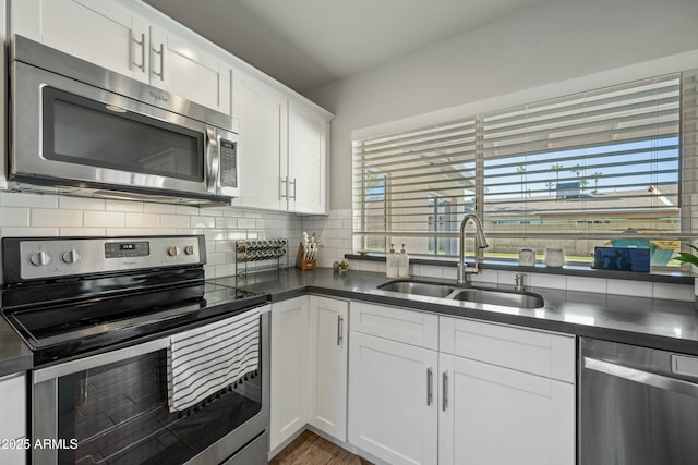 kitchen featuring appliances with stainless steel finishes, sink, white cabinets, and decorative backsplash