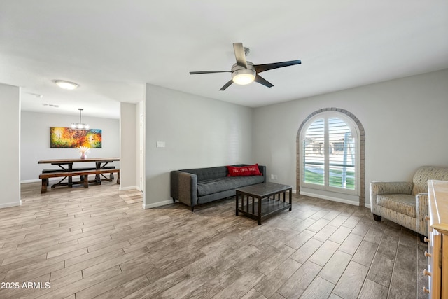 living room with ceiling fan with notable chandelier