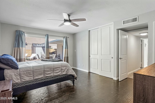 bedroom with dark hardwood / wood-style floors, a textured ceiling, ceiling fan, and a closet