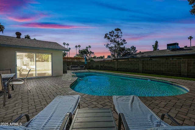 pool at dusk with a patio area