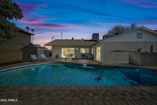 pool at dusk with a patio area