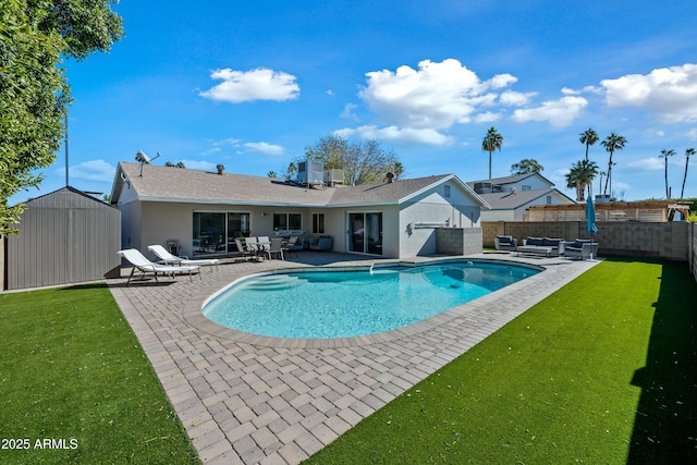 view of swimming pool featuring a patio, outdoor lounge area, a lawn, and a shed