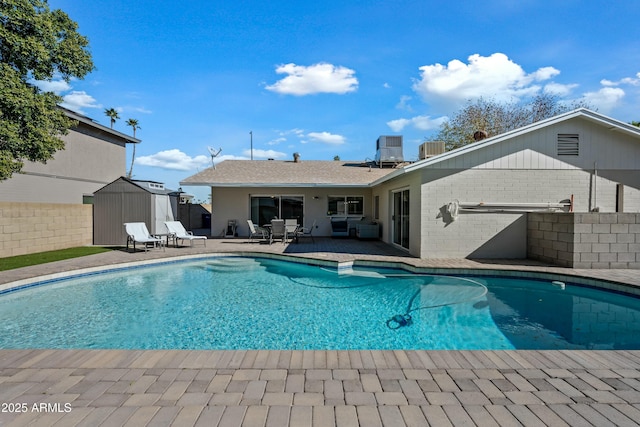 view of pool featuring a patio, central AC, and a storage unit