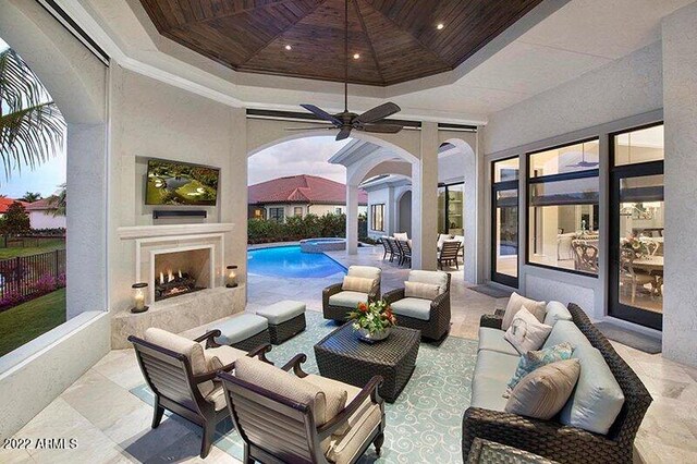 view of patio / terrace featuring a fenced in pool, ceiling fan, and an outdoor living space with a fireplace