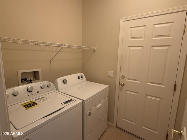 laundry area with independent washer and dryer and light tile patterned floors