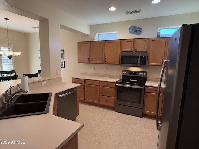 kitchen with appliances with stainless steel finishes, decorative light fixtures, sink, kitchen peninsula, and an inviting chandelier