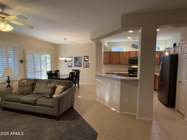 tiled living room with sink and ceiling fan with notable chandelier