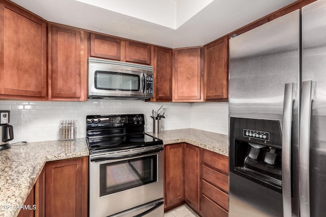 kitchen featuring brown cabinetry, backsplash, and appliances with stainless steel finishes