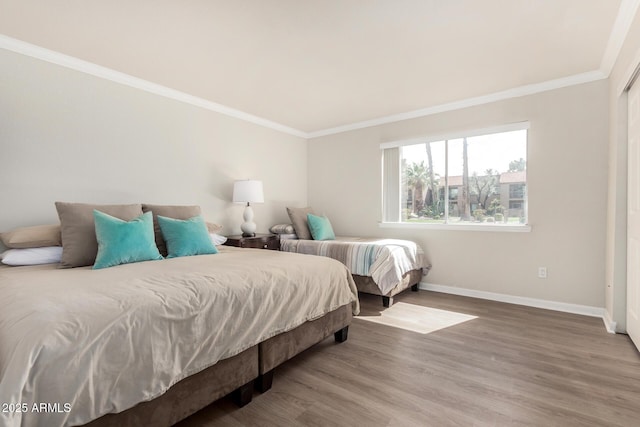 bedroom with baseboards, wood finished floors, and crown molding