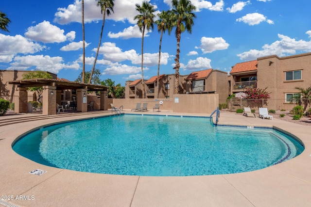 pool with fence, a pergola, and a patio area