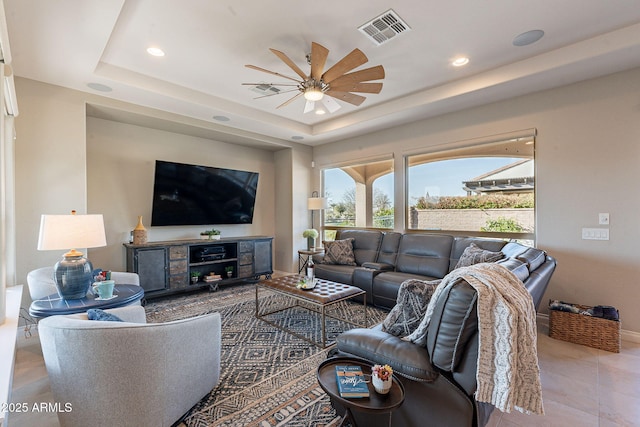 living room with visible vents, baseboards, a tray ceiling, recessed lighting, and a ceiling fan